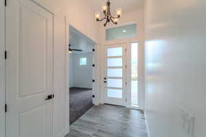 Entryway with light hardwood / wood-style floors and ceiling fan with notable chandelier