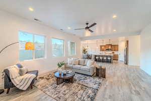 Living room with ceiling fan and light hardwood / wood-style floors