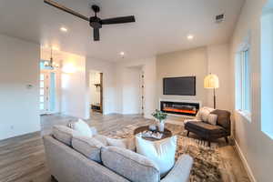 Living room with ceiling fan with notable chandelier, hardwood / wood-style flooring, and plenty of natural light