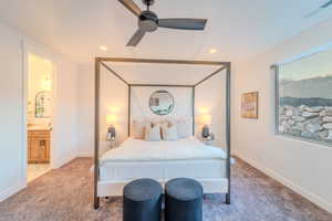 Bedroom with ensuite bathroom, light colored carpet, and ceiling fan