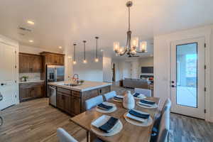 Kitchen with decorative light fixtures, stainless steel appliances, a center island with sink, an inviting chandelier, and sink