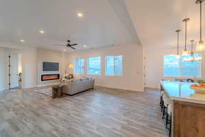 Living room featuring ceiling fan with notable chandelier and light wood-type flooring