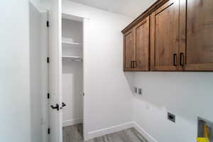 Washroom featuring hookup for an electric dryer, light hardwood / wood-style flooring, washer hookup, and cabinets