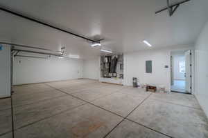 Garage featuring electric panel, a garage door opener, and water heater