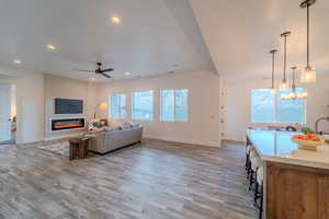 Living room with ceiling fan with notable chandelier and light hardwood / wood-style floors