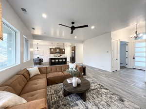 Living room with hardwood / wood-style flooring and ceiling fan with notable chandelier