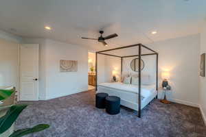 Bedroom featuring ceiling fan, ensuite bath, and dark carpet