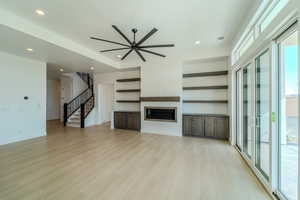 Unfurnished living room featuring ceiling fan and light hardwood / wood-style flooring