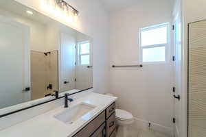 Bathroom with vanity, plenty of natural light, tile patterned floors, and toilet