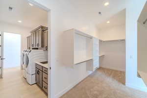 Interior space featuring washer and clothes dryer, cabinets, and light carpet