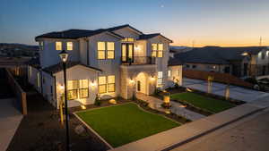 View of front of home with a balcony and a yard