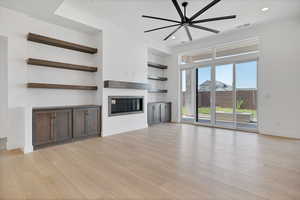 Unfurnished living room with a glass covered fireplace, light wood finished floors, a ceiling fan, and recessed lighting