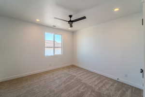 Carpeted spare room featuring ceiling fan