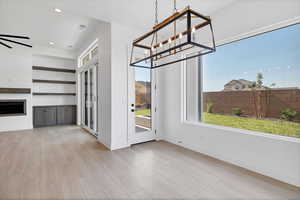 Unfurnished dining area with wood finished floors, recessed lighting, a fireplace, and a chandelier