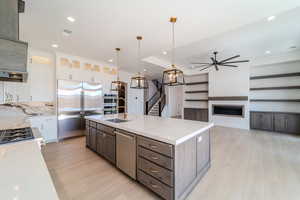 Kitchen featuring hanging light fixtures, white cabinetry, a kitchen island with sink, and appliances with stainless steel finishes