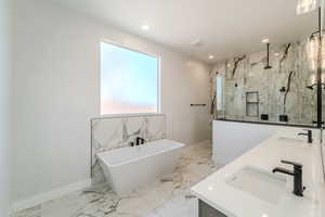 Bathroom featuring shower with separate bathtub and vanity