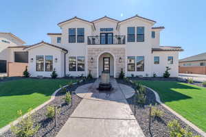 Mediterranean / spanish-style house featuring a front lawn and a balcony