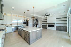 Kitchen featuring white cabinetry, appliances with stainless steel finishes, hanging light fixtures, sink, and a kitchen island with sink