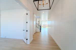 Hall featuring light wood-type flooring and a chandelier