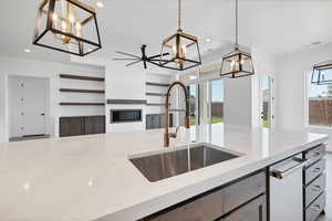 Kitchen featuring a chandelier, recessed lighting, decorative light fixtures, a glass covered fireplace, and light stone countertops