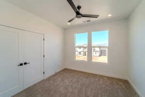 Unfurnished bedroom featuring ceiling fan, light carpet, and a closet