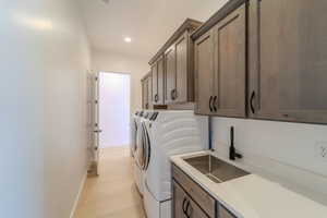 Laundry area with cabinets, light hardwood / wood-style floors, sink, and independent washer and dryer