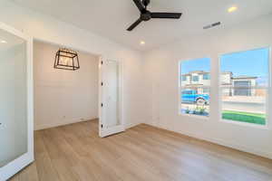 Empty room with french doors, light hardwood / wood-style floors, and ceiling fan with notable chandelier