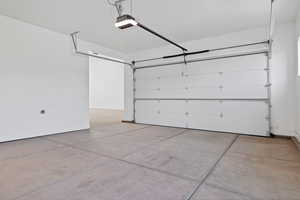 Garage featuring a garage door opener and baseboards