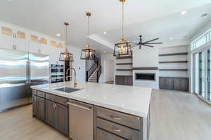 Kitchen featuring a center island with sink, stainless steel appliances, light wood-type flooring, hanging light fixtures, and white cabinets