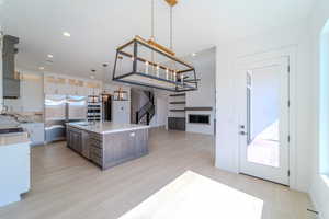 Kitchen featuring tasteful backsplash, stainless steel appliances, a kitchen island, pendant lighting, and light hardwood / wood-style floors