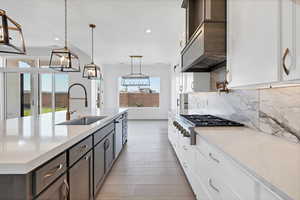 Kitchen with decorative backsplash, stainless steel gas stovetop, light wood-style floors, recessed lighting, and white cabinetry