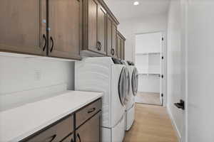 Washroom with washer and dryer, light wood-style flooring, cabinet space, and recessed lighting