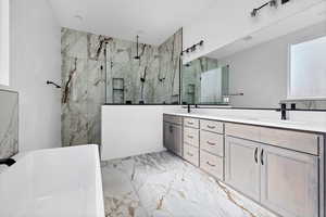 Full bathroom featuring marble tiled flooring, double vanity, a marble finish shower, and a freestanding tub