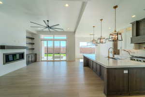 Kitchen featuring hanging light fixtures, sink, dark brown cabinetry, and a spacious island