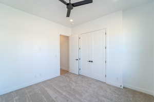 Unfurnished bedroom with light colored carpet, ceiling fan, and a closet