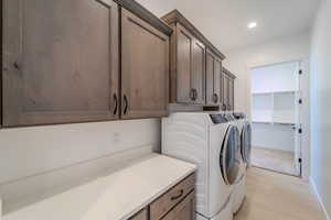 Clothes washing area with cabinets, light hardwood / wood-style floors, and separate washer and dryer