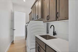 Laundry room with cabinet space, washer and clothes dryer, light wood-type flooring, and recessed lighting