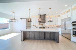 Kitchen with a spacious island, hanging light fixtures, a barn door, and stainless steel appliances