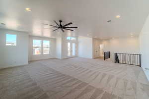 Unfurnished living room featuring french doors, light carpet, and ceiling fan