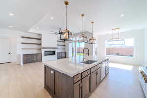 Kitchen featuring dark brown cabinetry, a center island with sink, plenty of natural light, and sink