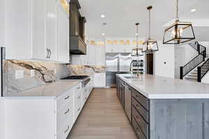 Kitchen with appliances with stainless steel finishes, light wood-style flooring, a chandelier, white cabinets, and recessed lighting