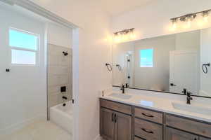 Bathroom featuring vanity, a wealth of natural light, tile patterned flooring, and tiled shower / bath