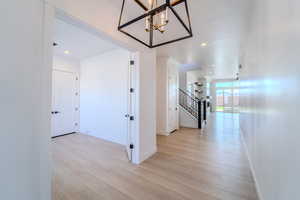 Corridor with a notable chandelier and light hardwood / wood-style flooring