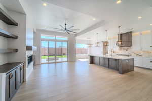 Kitchen with a kitchen island with sink, light wood-type flooring, decorative light fixtures, and custom exhaust hood