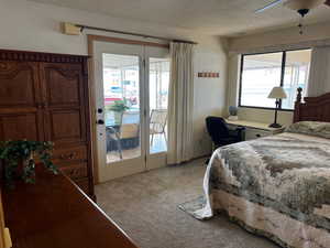 Carpeted bedroom featuring a textured ceiling, access to exterior, ceiling fan, and multiple windows