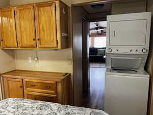 Interior space featuring dark hardwood / wood-style floors, ceiling fan, and stacked washer and dryer