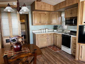 Kitchen featuring dark hardwood / wood-style flooring, white range oven, hanging light fixtures, and sink