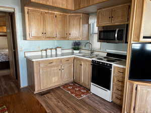 Kitchen with dark hardwood / wood-style floors, sink, and white stove