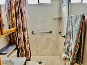 Bathroom featuring a shower with shower curtain, vanity, and toilet