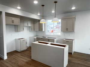 Kitchen featuring dark hardwood / wood-style floors, a kitchen island, hanging light fixtures, and gray cabinetry